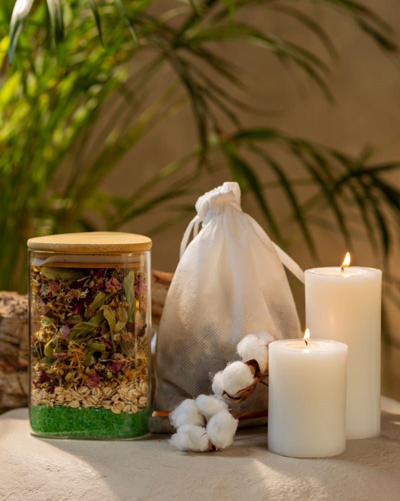 A jar of herbs and mine salts, a candle, and cotton bag full of herbal infusion arranged on a table, evoking a serene and calming atmosphere for self-care.